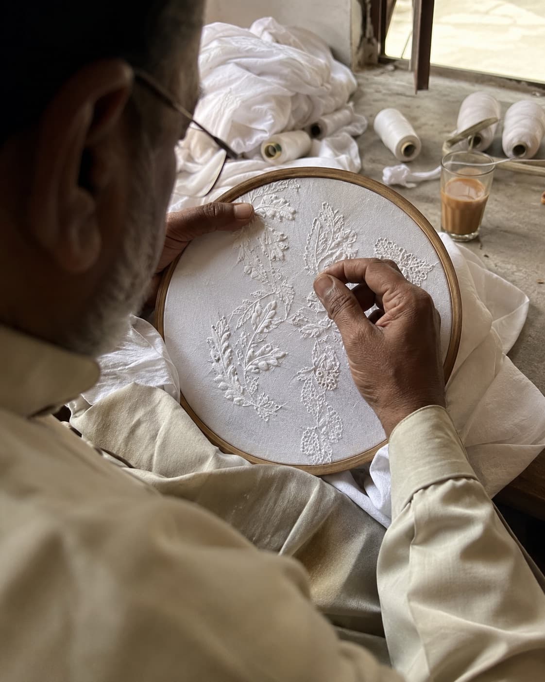 Dignified portrait of a senior woman karigar seated at an embroidery frame in a Lucknow workshop