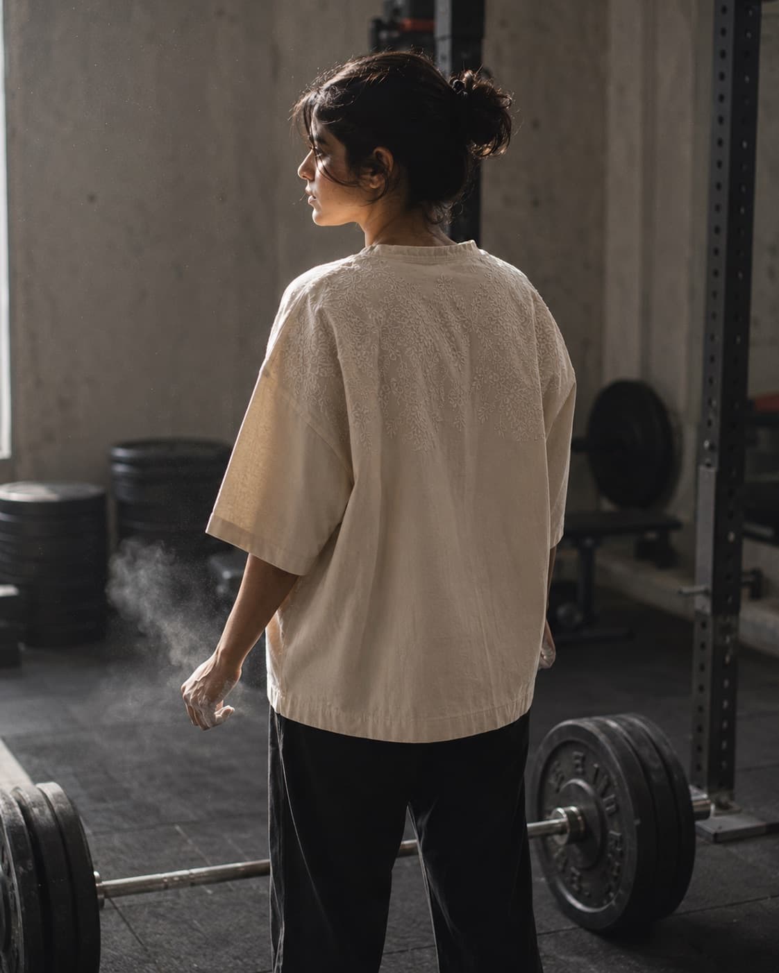 Woman in an oversized chikankari pump cover and track pants on a gym floor